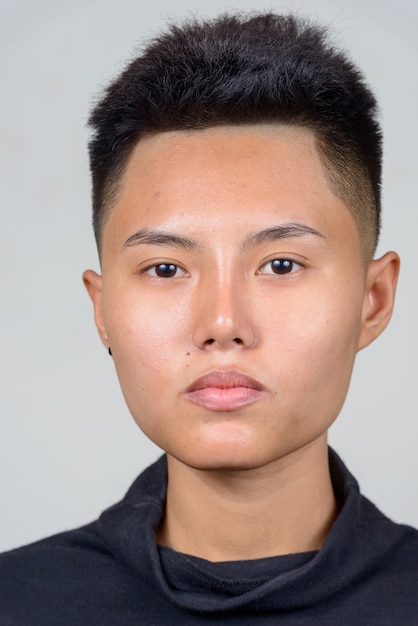 Studio shot of young Asian lesbian woman with short hair against white background