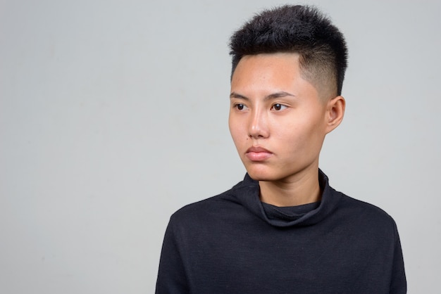 Studio shot of young Asian lesbian woman with short hair against white background