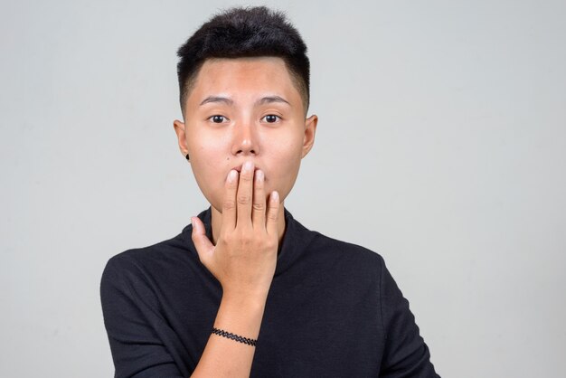 Studio shot of young Asian lesbian woman with short hair against white background