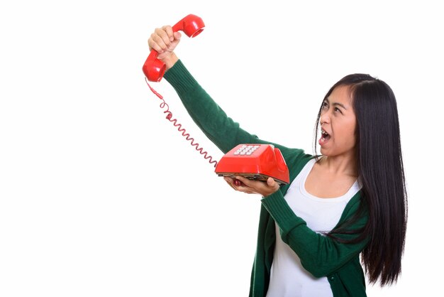 Studio shot of young Asian teenage girl holding old telephone