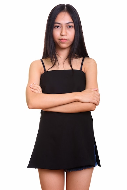 Studio shot of young Asian teenage girl standing with arms crossed