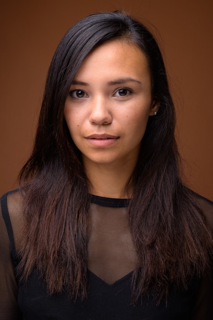 Studio shot of young Asian woman against brown background