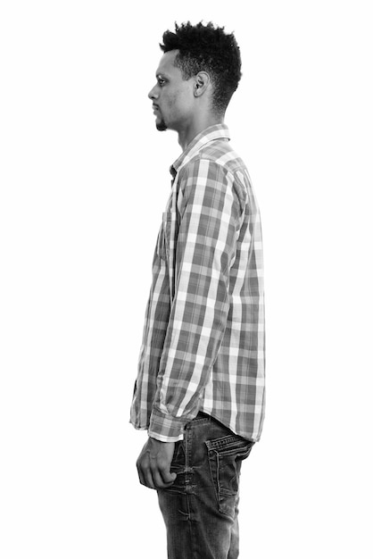 Studio shot of young bearded African businessman with afro hair isolated against white background in black and white