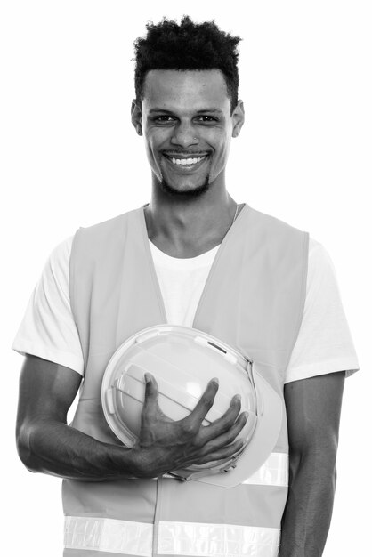 Studio shot of young bearded African man construction worker isolated against white background in black and white