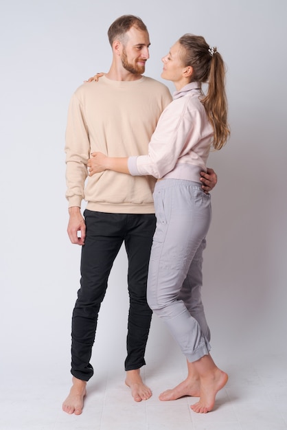 Studio shot of young bearded man and young beautiful woman together against white