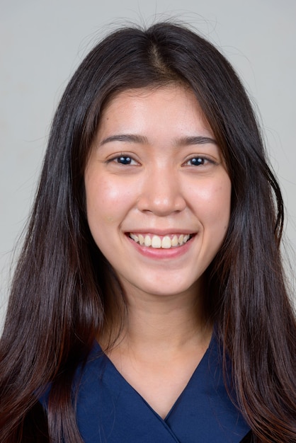 Studio shot of young beautiful Asian businesswoman against white background