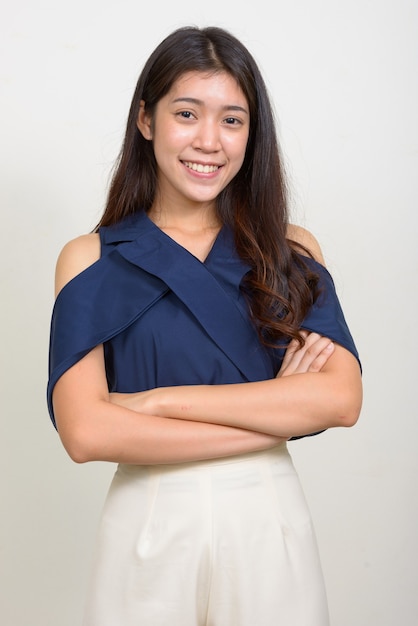 Studio shot of young beautiful Asian businesswoman against white background