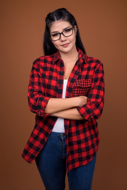 Studio shot of young beautiful Asian hipster woman with arms crossed