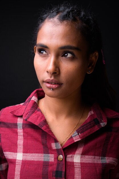 Studio shot of young beautiful Asian hipster woman with braided hair against black background