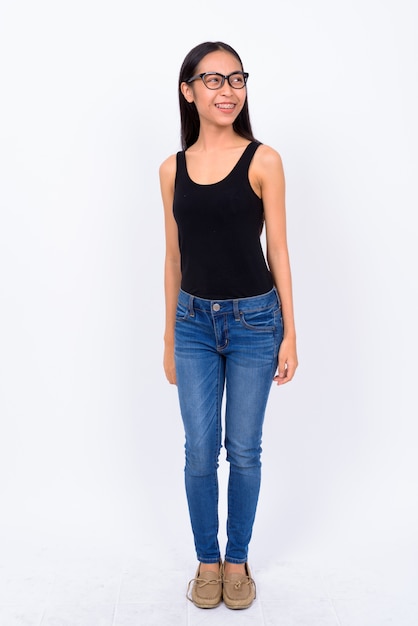 Studio shot of young beautiful Asian nerd woman with eyeglasses against white background