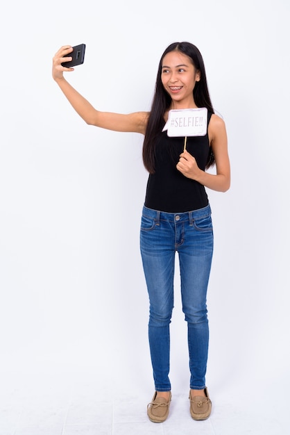 Studio shot of young beautiful Asian woman against white background