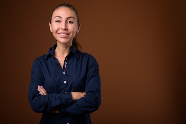 Studio shot of young beautiful businesswoman against brown background