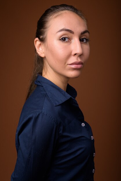 Photo studio shot of young beautiful businesswoman against brown background