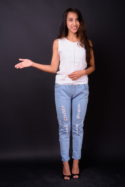 Studio shot of young beautiful Filipino woman against black background