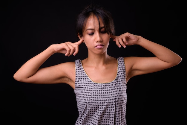 Studio shot of young beautiful Filipino woman against black background