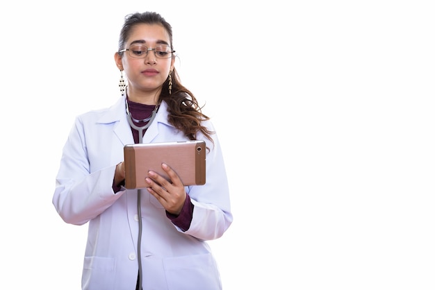 Studio shot of young beautiful Indian woman doctor using digital