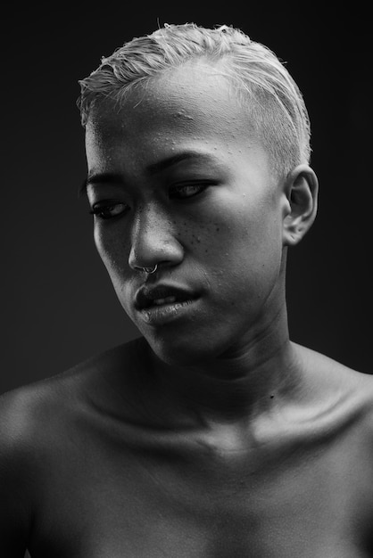 白と黒の灰色に対して短い髪の若い反抗的な女性のスタジオ撮影