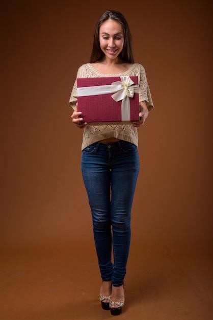 Studio shot of young beautiful woman against brown background