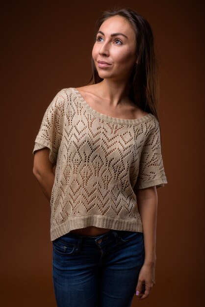 Studio shot of young beautiful woman against brown background