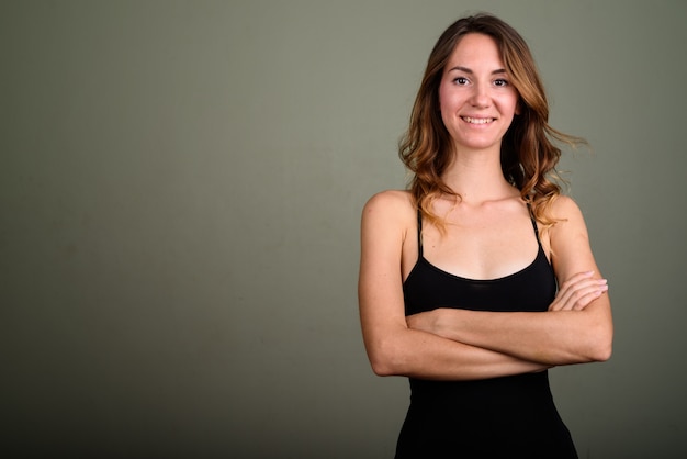 Studio shot of young beautiful woman wearing sleeveless top against colored background