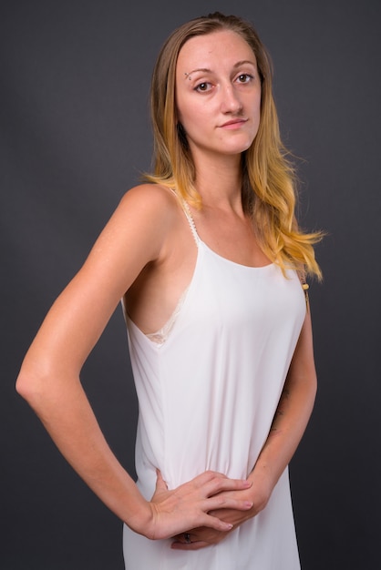 Studio shot of young beautiful woman with straight blond hair against gray