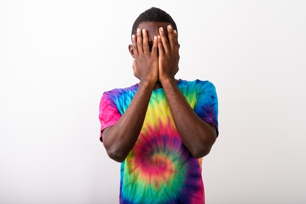 Studio shot of young black African man covering his face with bo