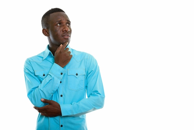 Studio shot of young black African man thinking while looking up