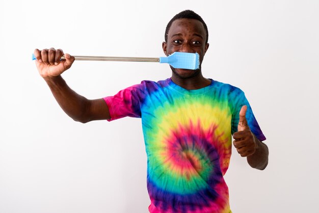 Studio shot of young black African man using big cleaning brush