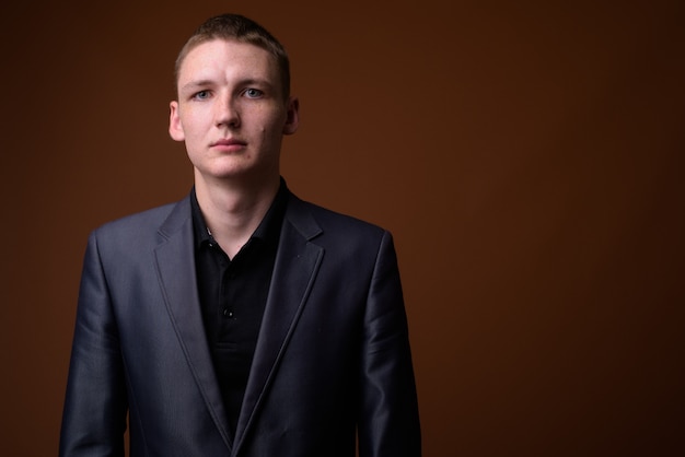 Studio shot of young businessman wearing suit against brown background