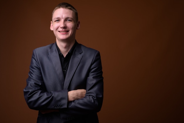 Studio shot of young businessman wearing suit against brown background