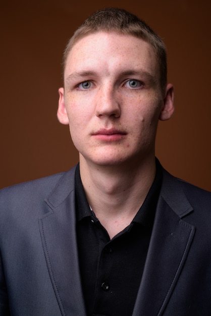 Studio shot of young businessman wearing suit against brown background