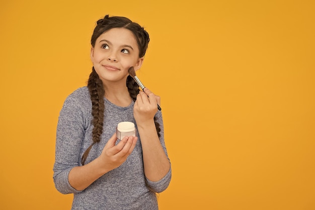 Studio shot of young girl doing make up beautiful teen girl doing makeup using powder brush skincare concept applying makeup on a healthy skin child make up products copy space