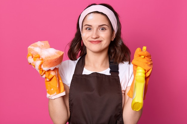 Studio shot of young good looking female holding brush and spray