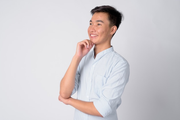 Studio shot of young handsome Asian businessman against white background