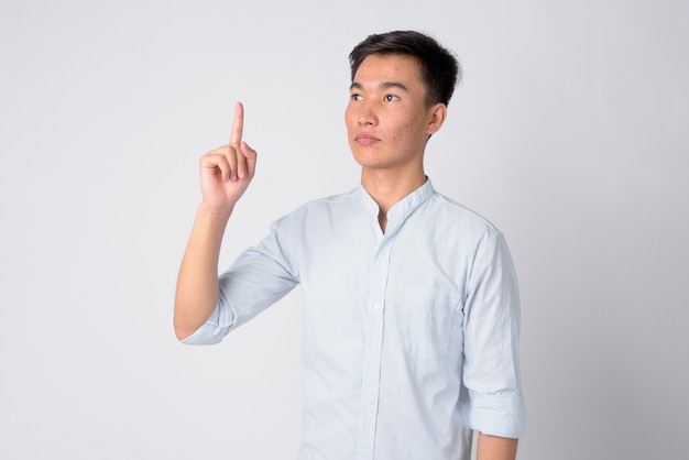 Studio shot of young handsome Asian businessman against white background