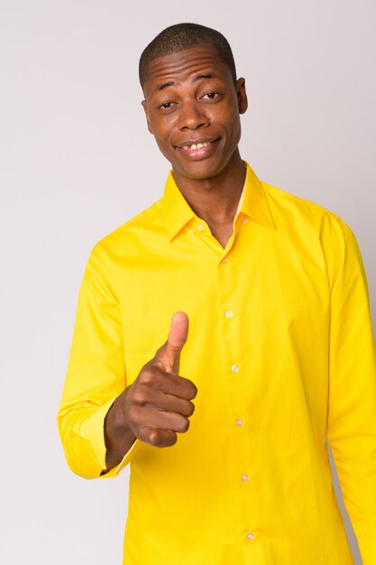 Studio shot of young handsome bald African businessman against white background