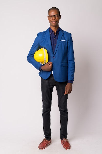 Studio shot of young handsome bald African businessman in suit with eyeglasses against white background