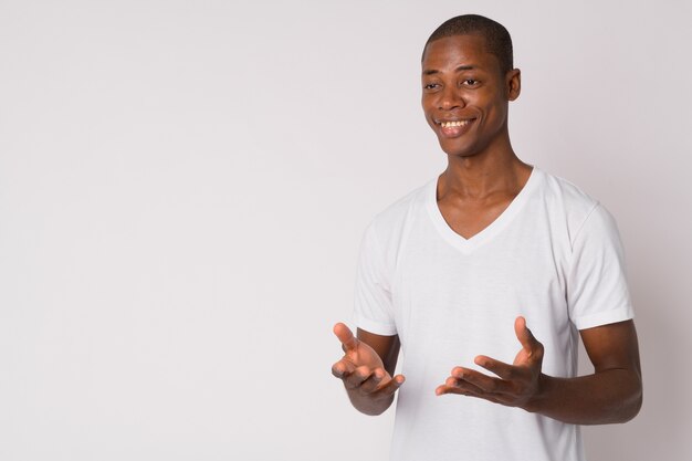 Studio shot of young handsome bald African man against white background