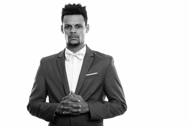 Studio shot of young handsome bearded African businessman in suit isolated against white background in black and white