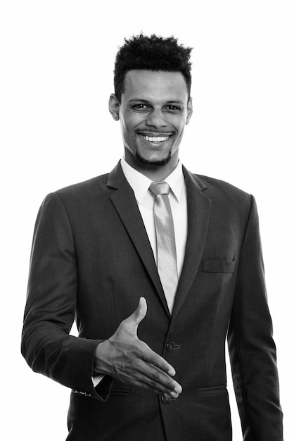 Studio shot of young handsome bearded African businessman in suit isolated against white background in black and white