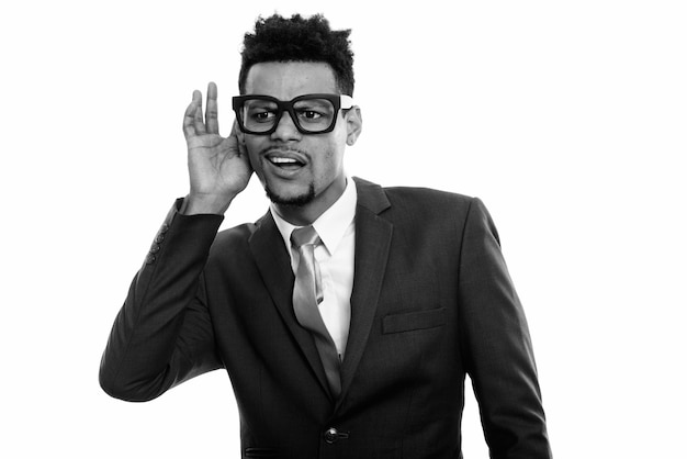 Studio shot of young handsome bearded African businessman in suit isolated against white background in black and white