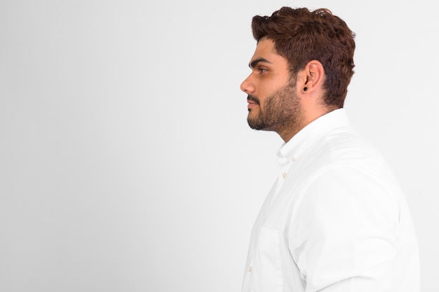 Studio shot of young handsome bearded Indian man against white