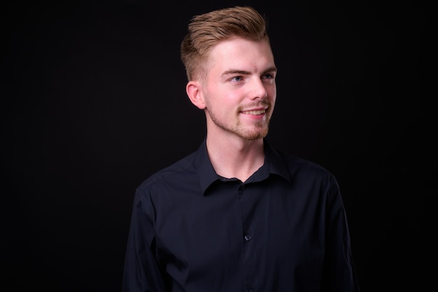 Studio shot of young handsome businessman against black background