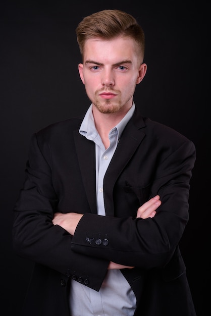 Studio shot of young handsome businessman against black background