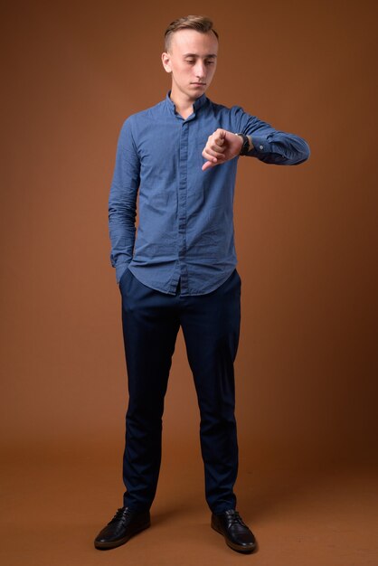 Studio shot of young handsome businessman against brown