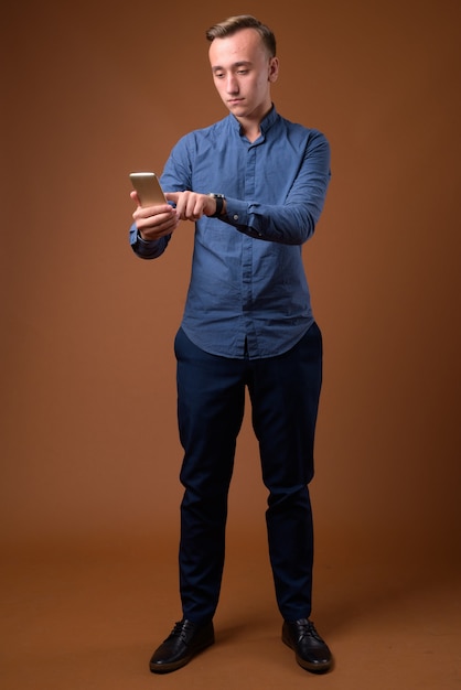 Studio shot of young handsome businessman against brown