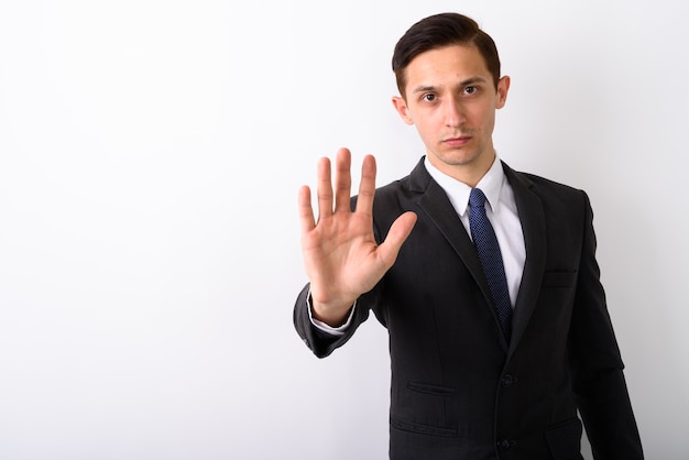 Studio shot of young handsome businessman showing stop hand sign