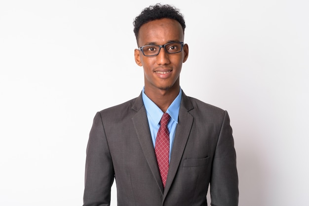 Studio shot of young handsome businessman with Afro hair wearing suit against white