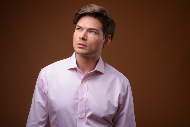 Studio shot of young handsome businessman with pink shirt