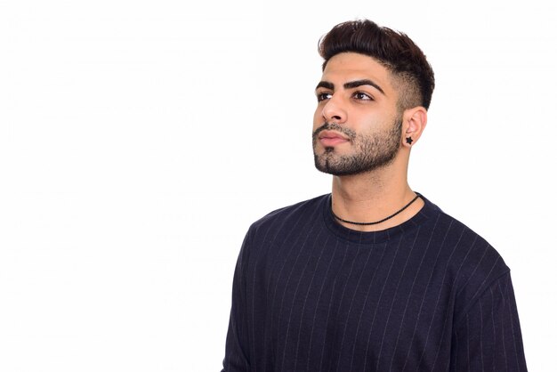 Studio shot of young handsome Indian man thinking isolated against white background